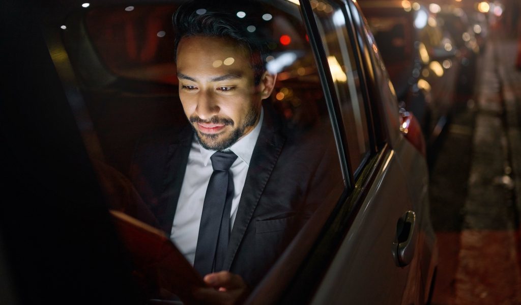 Man sitting in car looking at screen